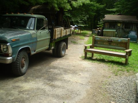 1979 Ford Bronco - A vintage Ford F-Series truck sits parked on a gravel driveway near a rustic wooden bench and outbuildings.