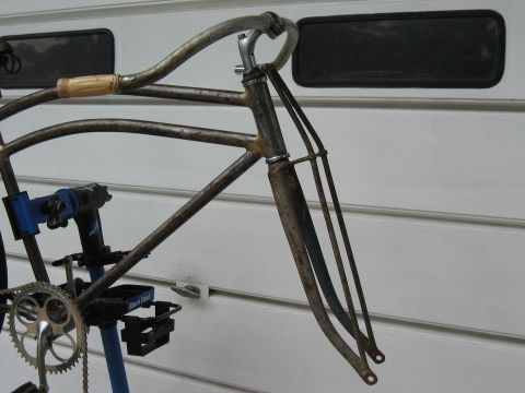 1994 Ford Bronco - A vintage bicycle frame and fork, showing signs of rust, is mounted on a repair stand. A crankset is attached to the frame.