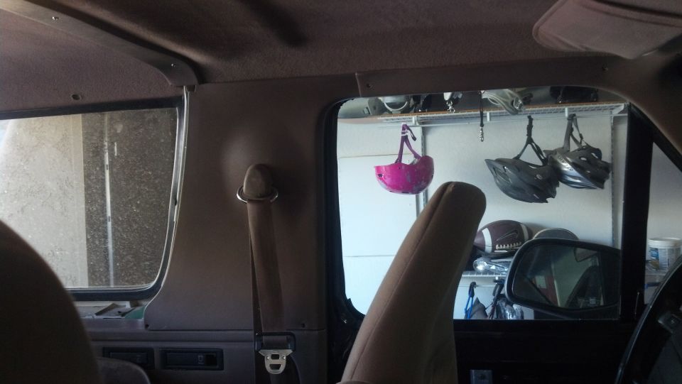Interior view of a vehicle with a pink helmet hanging from the ceiling