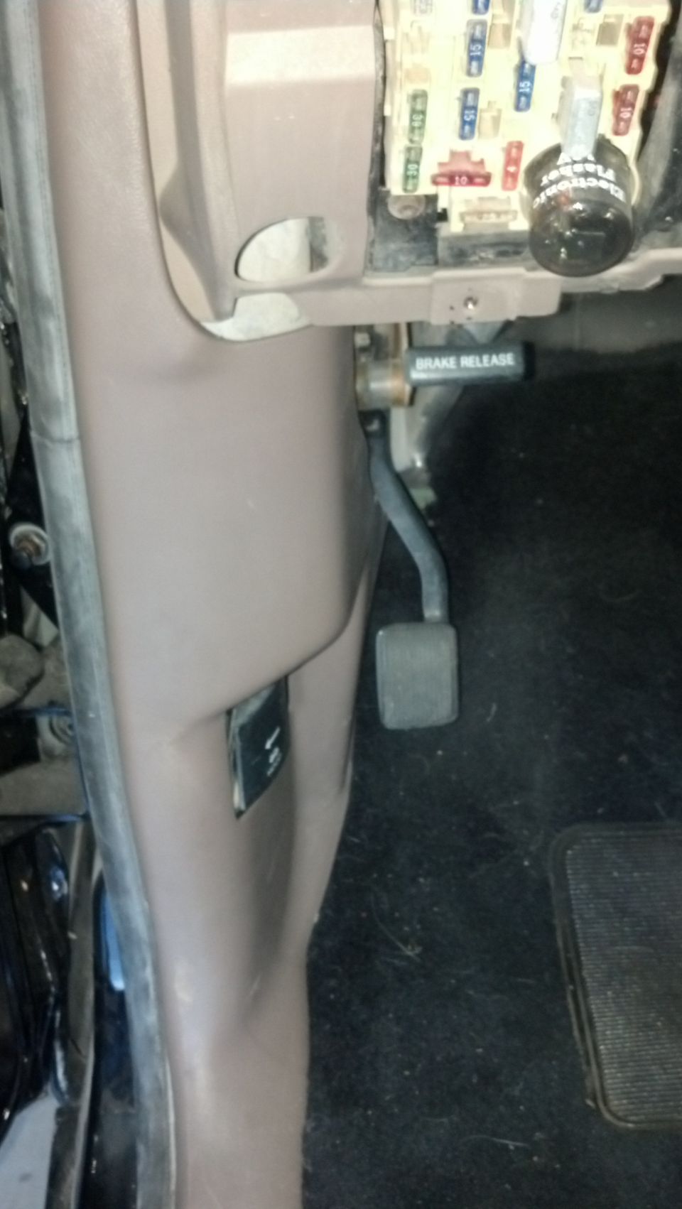 1995 Ford Bronco interior driver's side footwell with brake pedal, fuse box, and brake release lever