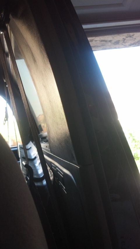 1995 Ford Bronco - View from inside the vehicle, focusing on the seatbelt and interior paneling with light filtering in.