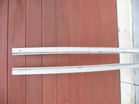 1993 Mazda MX-3 - Two white side skirts are shown against a red wooden wall, likely for a vehicle.