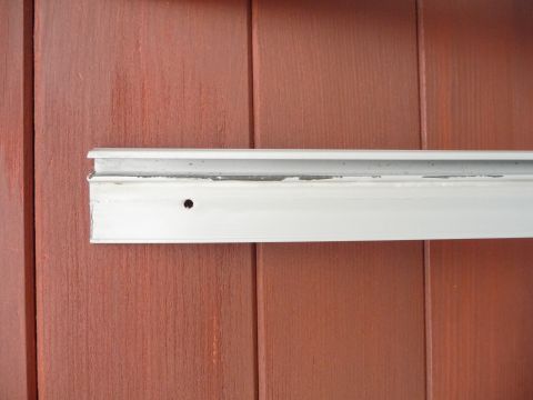 1993 Mazda MX-3 - Metal trim piece attached to wood siding, showing wear and a single drilled hole.