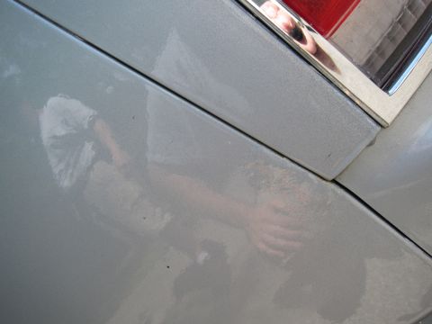 1991 Ford LTD Crown Victoria - A close-up view of a silver car panel shows a reflection of a person's arm and hand.