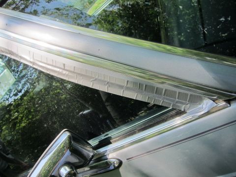1991 Ford LTD Crown Victoria - Close-up of the interior window trim on a 1991 Ford Crown Victoria LTD, showing chrome accents and a section covered with tape.