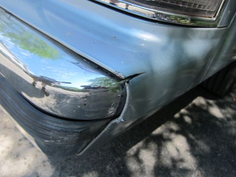 1991 Ford LTD Crown Victoria - Front corner of a car showing damage to the chrome bumper and fender.