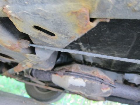 1991 Ford LTD Crown Victoria - The underside of a vehicle displays significant rust and a visible cable running along the frame.