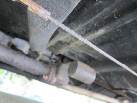 1991 Ford LTD Crown Victoria - Close-up view of the undercarriage components, including a rusted exhaust system and a cable.