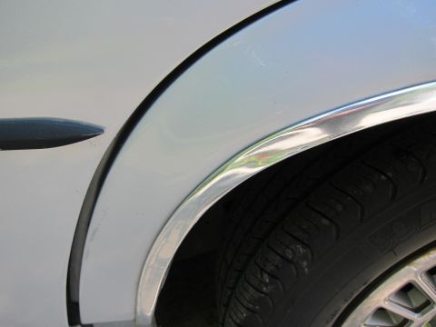1991 Ford LTD Crown Victoria - Detail of a car's fender and tire, showing chrome trim around the wheel well.