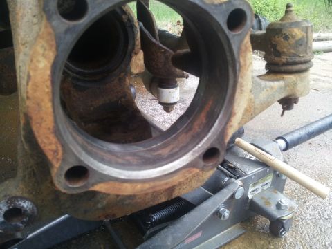 1988 Ford Bronco - Rusted vehicle suspension part being worked on with a floor jack. Text on jack reads 'SUPERMOTORS'.