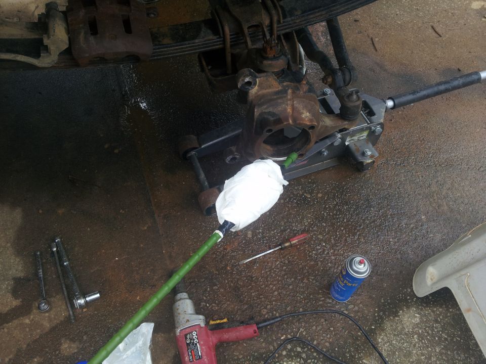 vehicle's front axle assembly on a jack with tools and spray can nearby