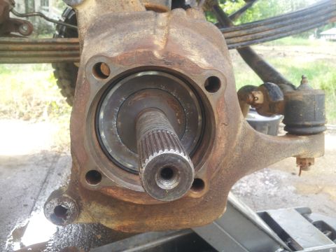 1988 Ford Bronco - Close-up of a heavily rusted wheel hub assembly, showing the splined axle shaft and tie rod end.