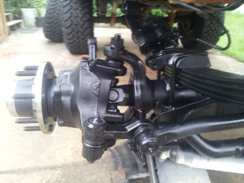 1988 Ford Bronco - Close-up of a vehicle's front axle assembly, showing suspension components and large tires.