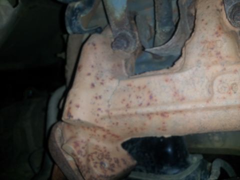 1988 Ford Bronco - Close-up view of a heavily rusted exhaust manifold, showing signs of wear and a crack.