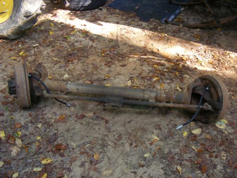 1978 Ford Bronco - A rear axle assembly lies on the ground, surrounded by fallen leaves.
