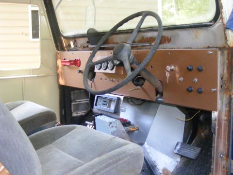 1978 Ford Bronco - The interior of a modified vehicle shows a custom dash panel with gauges, switches, and an old radio.