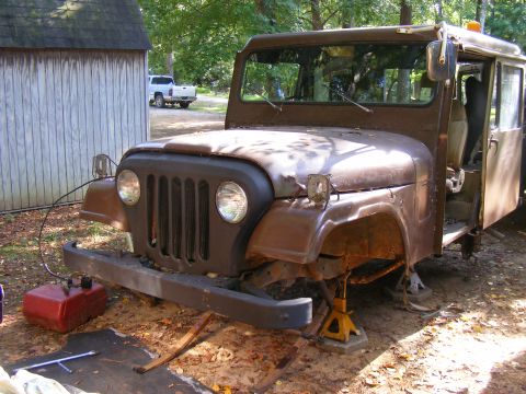 1978 Ford Bronco - A rusty Jeep CJ-5 sits on jack stands in front of a shed, with another truck visible in the background.