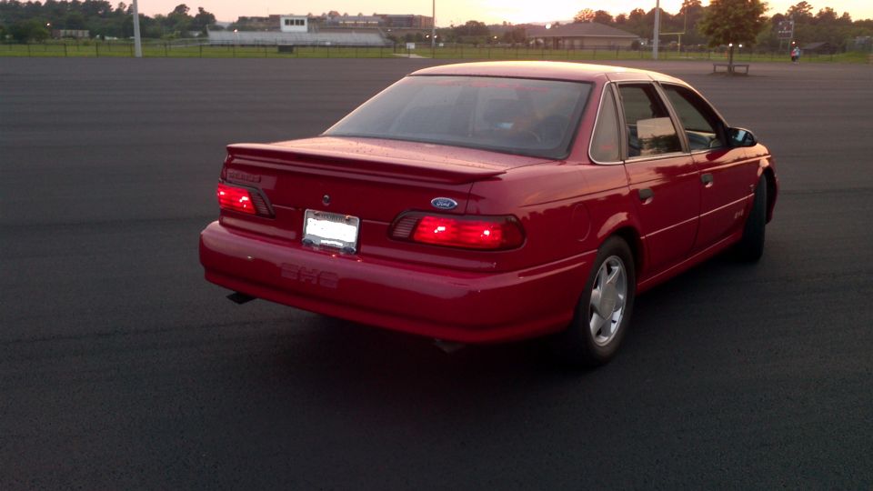 Red sedan with a spoiler and a license plate, viewed from the rear