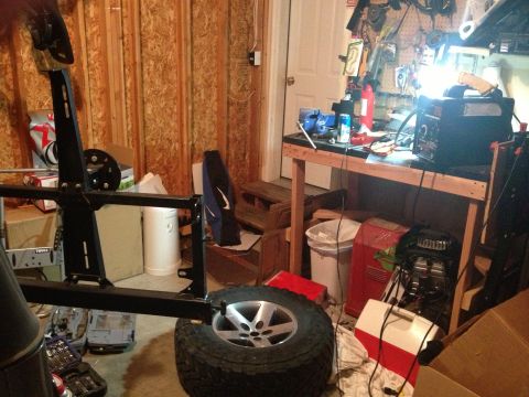 2005 Jeep Wrangler - A spare tire carrier and wheel are visible in a cluttered workshop setting, with tools and equipment in the background.