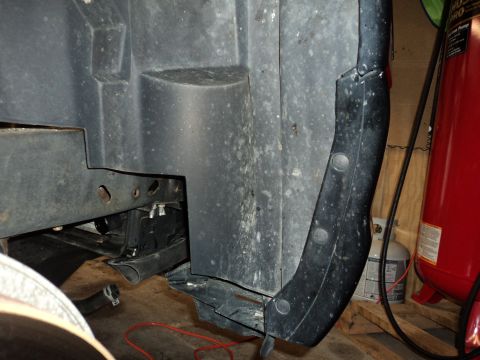 2004 Mercury Grand Marquis - Detail of a vehicle's wheel well liner and frame components, showing the underside of the body.