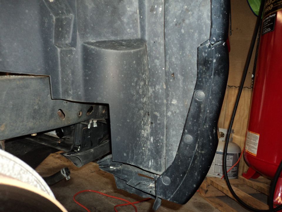 Close-up of a vehicle's inner fender liner and frame structure, with some wiring visible
