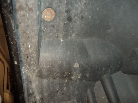 2004 Mercury Grand Marquis - Close-up of a dirty wheel well liner showing a rusty bolt and part of a tire.
