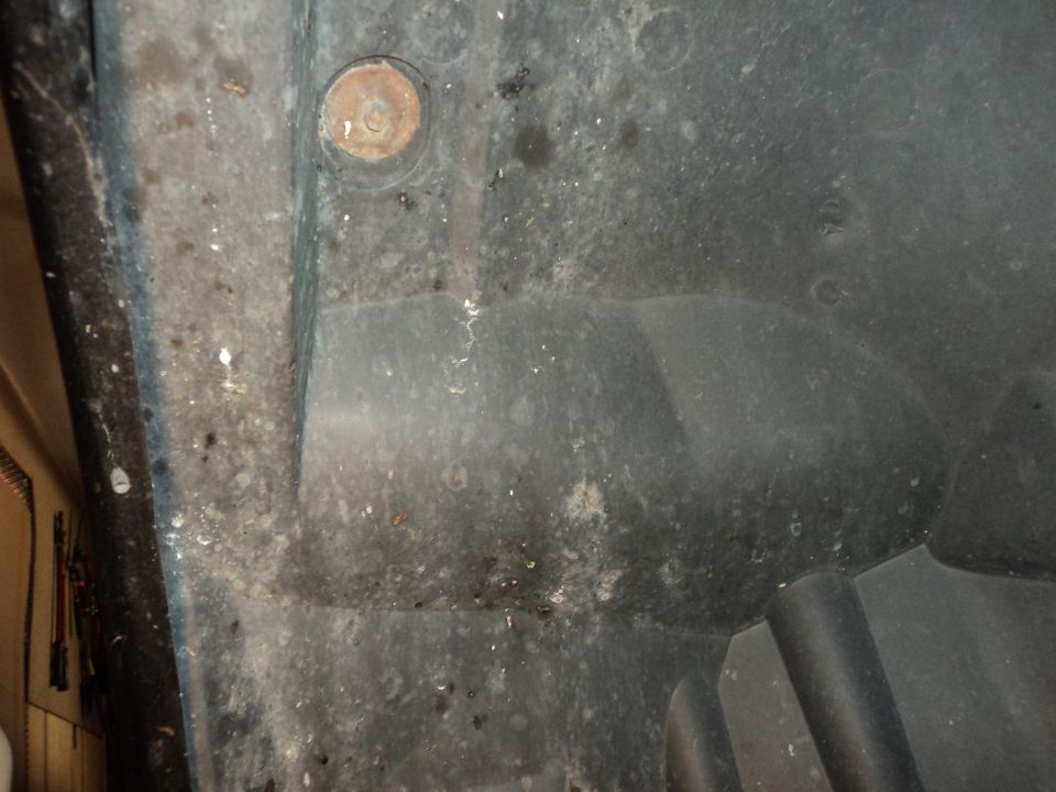 Black plastic wheel well liner with a rusty bolt and tire tread visible