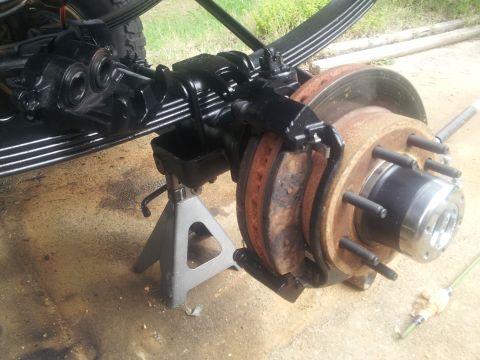 1988 Ford Bronco - The front axle and brake system of a vehicle are shown, supported by jack stands for maintenance.