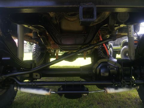 1988 Ford Bronco - The photo shows the undercarriage of a truck, focusing on the rear axle and suspension components. Another vehicle is visible in the backgr…