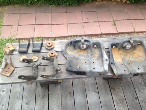 1986 Ford Bronco - A collection of used vehicle suspension parts are displayed outdoors on a wooden bench.