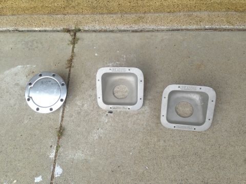 1986 Ford Bronco - Two square bezels and a circular cap, possibly for a vehicle, are displayed on a concrete ground.