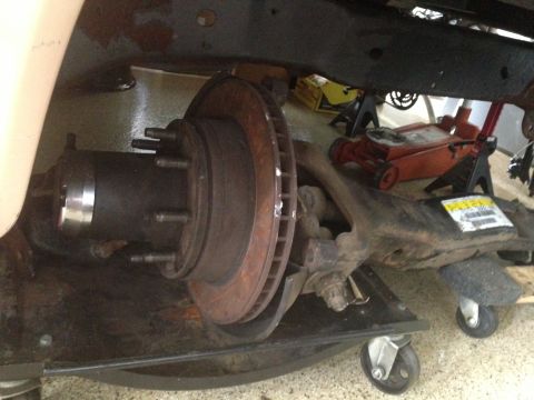 1986 Ford Bronco - Close-up of a vehicle's front suspension and braking system, undergoing maintenance.