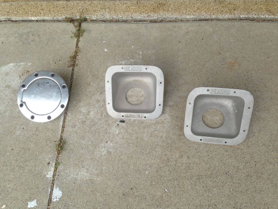 Two square aluminum housings and a round cap with bolts on concrete