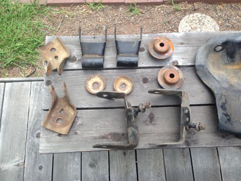 1986 Ford Bronco - Several rusty vehicle suspension components and a piece of bodywork are displayed on a weathered wooden surface.