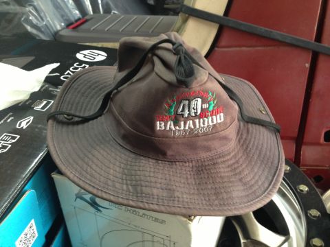 1986 Ford Bronco - A hat commemorating the Baja 1000 event is placed in front of a red interior, with various boxes and a wheel visible.