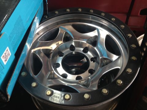 1986 Ford Bronco - A close-up view of a chrome wheel with a black beadlock, showing some visible text on the rim.