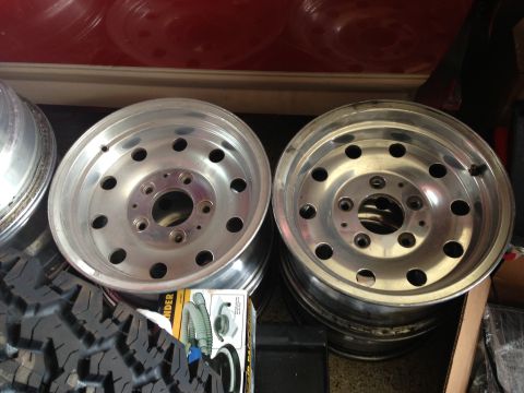 1986 Ford Bronco - Two aluminum alloy wheels with a 5x5.5 bolt pattern are shown next to a mud-terrain tire.