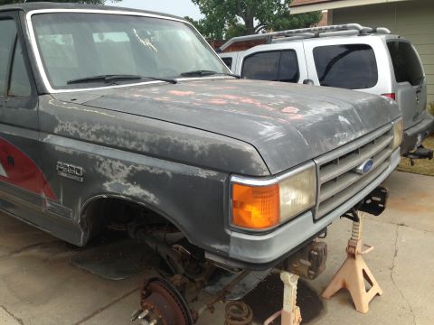 1986 Ford Bronco - This Ford F-250 truck is missing its front wheels and has significant paint damage, indicating it is undergoing repairs or restoration.
