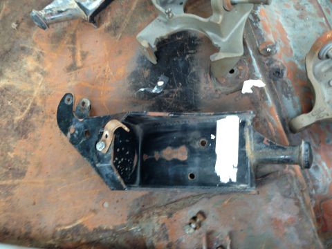 1986 Ford Bronco - A close-up view of a black metal bracket assembly with visible rust and white paint markings.