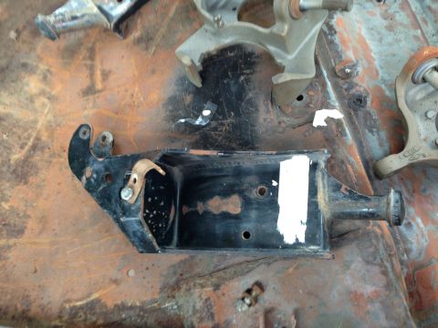 1986 Ford Bronco - A black metal bracket with white paint marks is shown on a rusty surface, likely a vehicle part.
