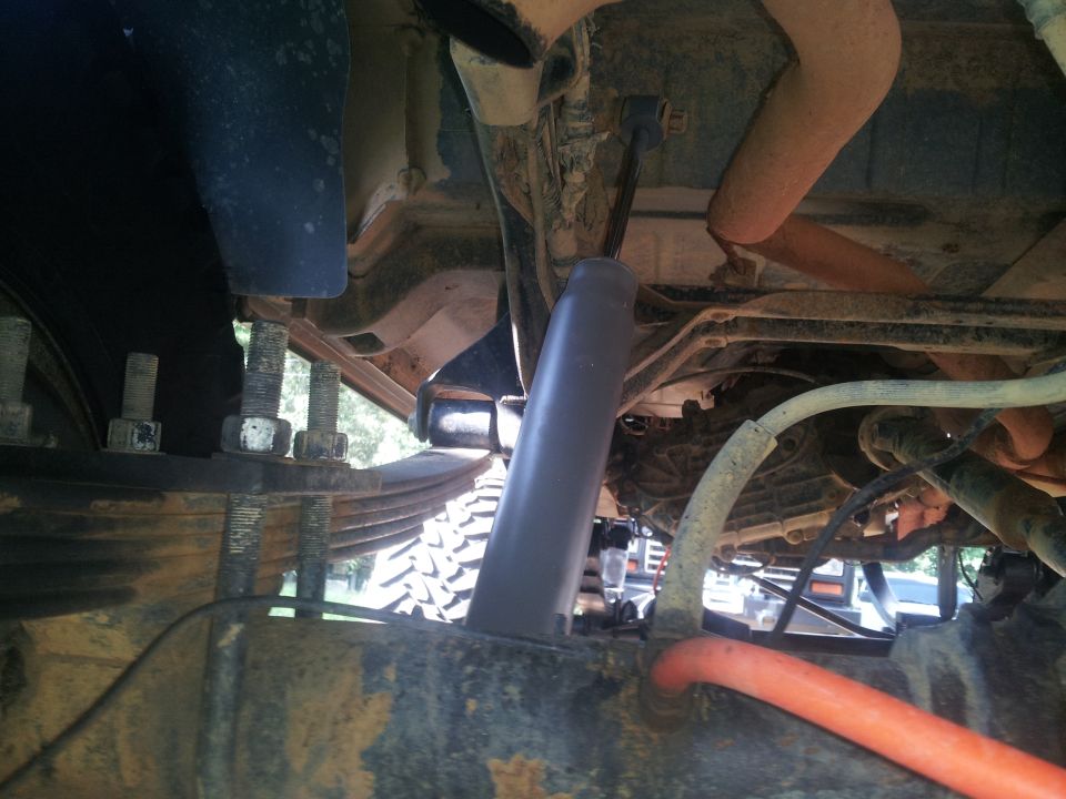 close-up of leaf springs, shock absorber, and exhaust pipe on a truck's undercarriage
