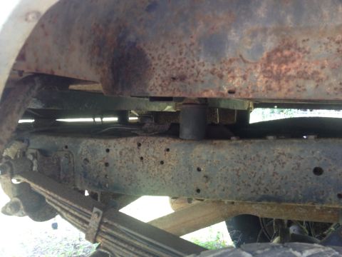 Close-up of heavily rusted vehicle frame and leaf spring suspension components