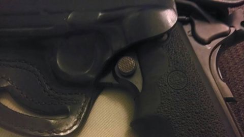 2000 Mercury Grand Marquis - A black handgun is partially visible within its leather holster, with a textured grip and a checkered release button.