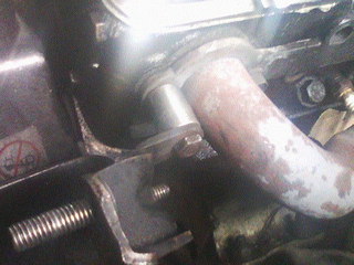 1975 Chevrolet Chevelle - Close-up of an exhaust manifold bolt and pipe connection, showing SuperMotors branding.