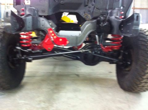 1982 Ford Bronco - The underside of a vehicle shows its suspension system and large tires, with a watermark for Supermotors.net.
