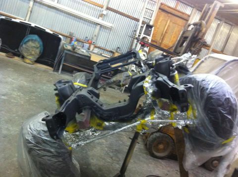 1982 Ford Bronco - Frame and suspension parts are being prepped for work in a garage.