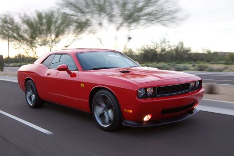 2010 Dodge Challenger - A red Dodge Challenger is captured in motion on a highway, its distinctive front-end design.
