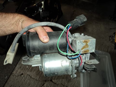 2004 Mercury Grand Marquis - A hand holds an air suspension compressor assembly, a component of a vehicle's suspension system.