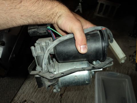 2004 Mercury Grand Marquis - A hand holds an air suspension compressor, likely for a vehicle's suspension system.