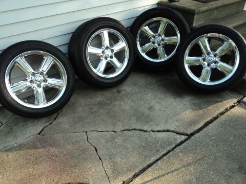 2004 Mercury Grand Marquis - Set of four chrome wheels and tires are displayed on a cracked concrete surface.